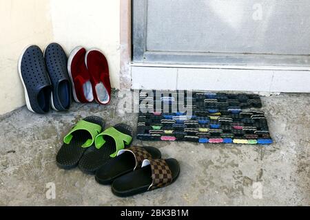 Foto von Schuhen und Pantoffeln an der Tür eines Hauses. Stockfoto