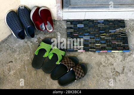 Foto von Schuhen und Pantoffeln an der Tür eines Hauses. Stockfoto