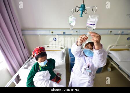 Qiandongnan, Chinas Provinz Guizhou. Mai 2020. Ein medizinischer Mitarbeiter kümmert sich um einen Patienten in einem Krankenhaus im Bezirk Danzhai von Qiandongnan Miao und der autonomen Präfektur Dong, Provinz Guizhou, im Südwesten Chinas, 1. Mai 2020. Während des Feiertags des Labor Day bleiben Menschen aus verschiedenen Sektoren an ihren Posten. Kredit: Yang Wukui/Xinhua/Alamy Live News Stockfoto