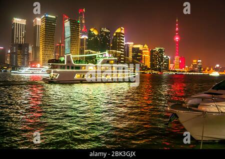 Besetzt den Fluss Huangpu Szene mit einem Ausflugsboot, der zwischen einer Luxusyacht und die beleuchtete Skyline von Pudong. Stockfoto