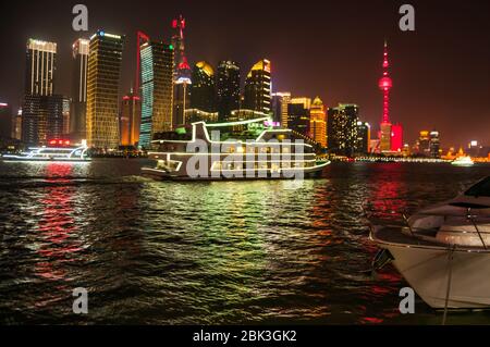Besetzt den Fluss Huangpu Szene mit einem Ausflugsboot, der zwischen einer Luxusyacht und die beleuchtete Skyline von Pudong. Stockfoto