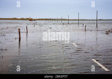 Der überflutete Damm auf Lindisfarne Island mit dem Emergency Refuge Box und Straßenmarkierungen, Northumberland, England Stockfoto