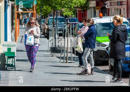 Clonakilty, West Cork, Irland. Mai 2020. Eine Schlange vor Clonakilty Apotheke in Clonakilty Main Street. Alle Apotheken erlauben aufgrund des Covid-19 Coronavirus nur jeweils eine Person im Laden. Credit: AG News/Alamy Live News. Stockfoto