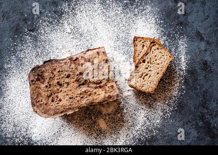 Hausgemachtes Sauerteig-Roggenbrot und weißes Mehl auf schwarzem Hintergrund. Kopierbereich Stockfoto