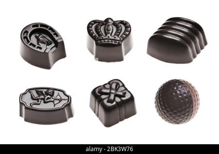 Luxuriöse dunkle Schokoladentrüffel. Verschiedene köstliche handgemachte Pralinen in einer Reihe auf weiß isoliert. Studioaufnahme. Nahaufnahme. Stockfoto