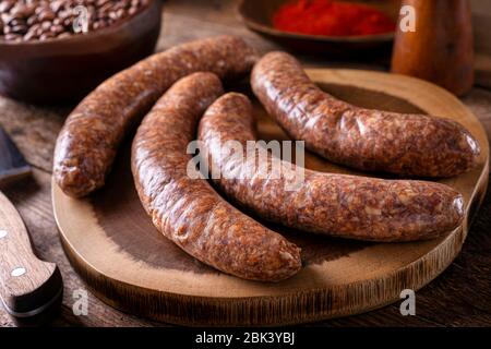 Frisch zubereitete rustikale Würstchen auf einem Holzbrett. Stockfoto