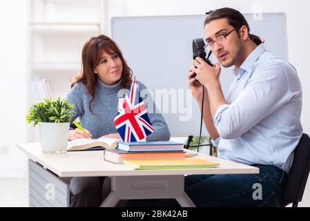 Junger Schüler und männlicher englischlehrer im Klassenzimmer Stockfoto