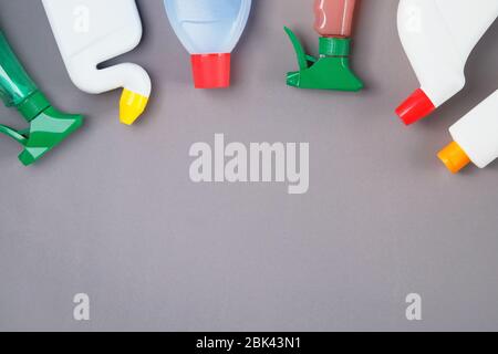 Flache Verlegung von Reinigungs- und Waschmitteln auf grauem Hintergrund. Waschmittel in Plastikflaschen und Spray. Servicekonzept. Draufsicht. Kopierbereich. Stockfoto