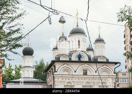 Moskau, Russland - 7. JULI 2017: Kaukasischer Arbeiter in blauem Overall repariert das Dach einer orthodoxen Kirche in Moskau Stockfoto