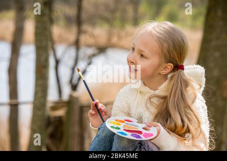 Das kleine Mädchen malt im Frühling auf die Natur Stockfoto
