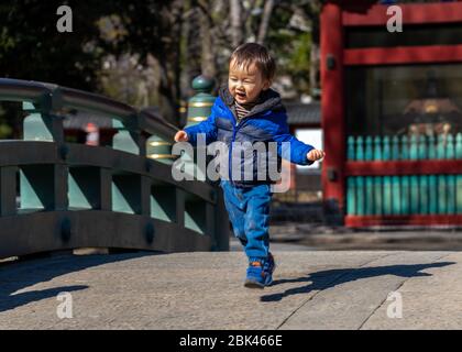 Kind läuft über die Brücke am Nezu Shrine, Tokyo Stockfoto