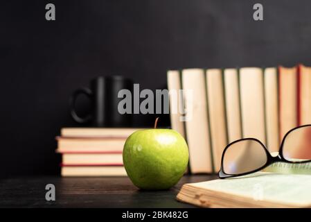 Stapel von Büchern mit einer Tasse Kaffee zum Lesen auf einem dunklen Tisch mit Kopierraum Stockfoto