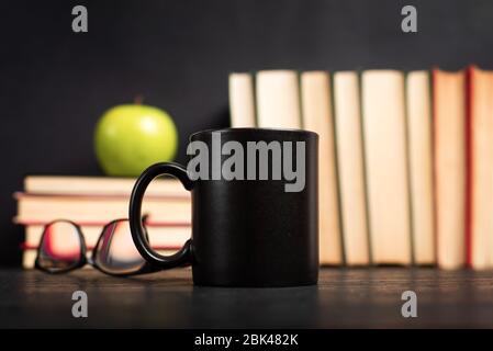 Stapel von Büchern mit einer Tasse Kaffee zum Lesen auf einem dunklen Tisch mit Kopierraum Stockfoto