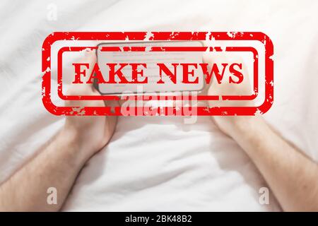 Fake News Infosemics during Covid-19 Pandemie Concept. Mann hält Handy und liest zu Hause Nachrichten oder soziale Netzwerke. Letzte News lesen upd Stockfoto