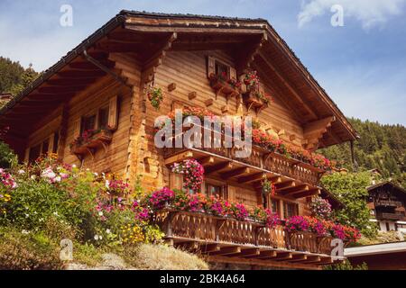 Ein schönes Holzhaus mit Blumen auf den Balkonen im Schweizer Alpendorf Grimentz im Kanton Wallis. Anniviers, Schweiz Stockfoto