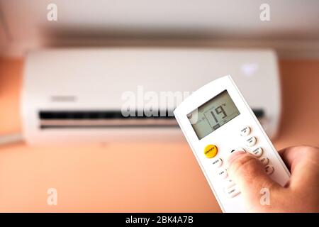 Split Air conditioner, Man operating remote controller Stockfoto