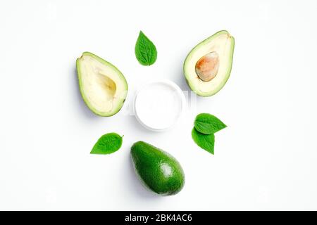 Frische Avocado und Glas Feuchtigkeitscreme auf weißem Hintergrund. Flach liegend, Draufsicht. SPA natürliche organische Kosmetik-Produkt, Hand und Körper Hautpflege Konz Stockfoto