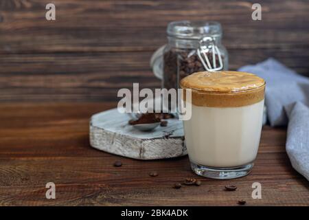 Dalgona Kaffee ist ein trendiges kaltes koreanisches Getränk. Geschmackvoller, aromatischer Kaffee mit Milch und Zucker in einem Glas auf Holzuntergrund. Kopierbereich Stockfoto