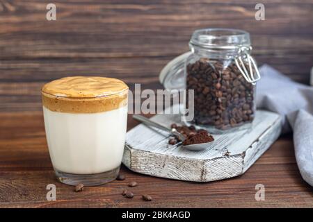 Dalgona Kaffee ist ein trendiges kaltes koreanisches Getränk. Geschmackvoller, aromatischer Kaffee mit Milch und Zucker in einem Glas auf Holzuntergrund. Kopierbereich Stockfoto