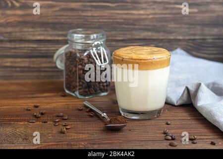 Dalgona Kaffee ist ein trendiges kaltes koreanisches Getränk. Geschmackvoller, aromatischer Kaffee mit Milch und Zucker in einem Glas auf Holzuntergrund. Kopierbereich Stockfoto