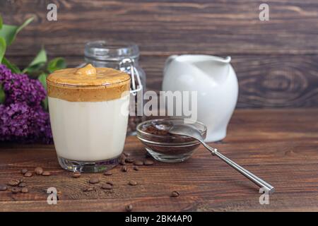 Dalgona Kaffee ist ein trendiges kaltes koreanisches Getränk. Geschmackvoller, aromatischer Kaffee mit Milch und Zucker in einem Glas auf Holzuntergrund. Kopierbereich Stockfoto