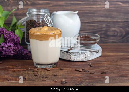 Dalgona Kaffee ist ein trendiges kaltes koreanisches Getränk. Geschmackvoller, aromatischer Kaffee mit Milch und Zucker in einem Glas auf Holzuntergrund. Kopierbereich Stockfoto