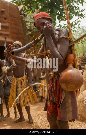 Ein Musiker benutzt ein Tierhorn während der traditionellen Tammari Tänze in ihren Familien Mudbrick Gebäude namens Tata oder Takienta (UNESCO World Heritag Stockfoto