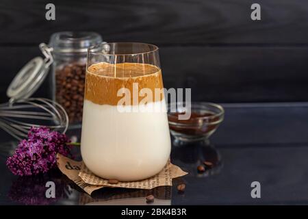 Dalgona Kaffee ist ein trendiges kaltes koreanisches Getränk. Geschmackvoller, aromatischer Kaffee mit Milch und Zucker in einem Glas auf schwarzem Hintergrund. Kopierbereich Stockfoto