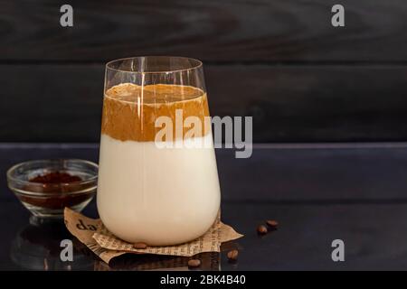 Dalgona Kaffee ist ein trendiges kaltes koreanisches Getränk. Geschmackvoller, aromatischer Kaffee mit Milch und Zucker in einem Glas auf schwarzem Hintergrund. Kopierbereich Stockfoto