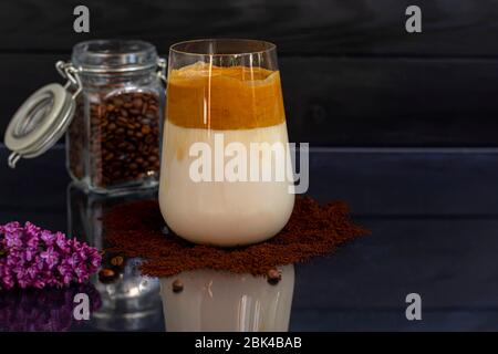 Dalgona Kaffee ist ein trendiges kaltes koreanisches Getränk. Geschmackvoller, aromatischer Kaffee mit Milch und Zucker in einem Glas auf schwarzem Hintergrund. Kopierbereich Stockfoto