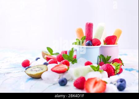 Hausgemachte Erdbeerpopsicles mit Eis, verschiedenen Beeren und Minze. Sommer gesundes Essen Konzept mit Kopierraum. Fruchteis mit verschiedenen Geschmacksrichtungen. Stockfoto