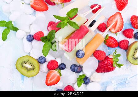 Hausgemachte Erdbeerpopsicles mit Eis, verschiedenen Beeren und Minze. Sommer gesundes Essen Konzept mit Kopierraum. Fruchteis mit verschiedenen Geschmacksrichtungen. Stockfoto