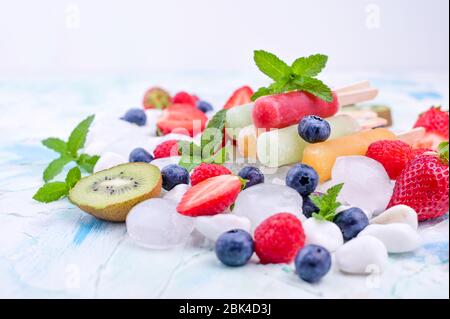 Hausgemachte Erdbeerpopsicles mit Eis, verschiedenen Beeren und Minze. Sommer gesundes Essen Konzept mit Kopierraum. Fruchteis mit verschiedenen Geschmacksrichtungen. Stockfoto