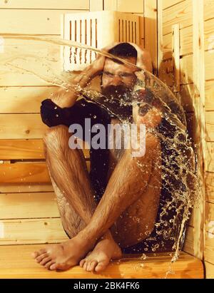 Schöner Mann oder Badende, bärtigen Hipster mit Bart und Schnurrbart in rot kariertem Hemd nass mit Big Splash von Wasser in Sauna, Thermalbad auf hölzernen Hintergrund Stockfoto