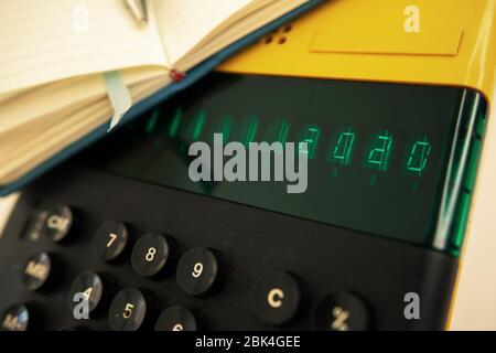 Altes Computermodell aus den 80er Jahren auf weißem Hintergrund, es ist eingeschaltet, es schreibt 2020 und ein Notizbuch mit einem Stift bereit für Notizen. Stockfoto