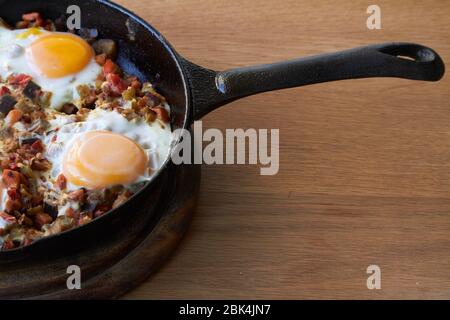 Hintergrund der Speisen, Spiegeleier mit Gemüse in der Pfanne auf Holztisch, selektive Fokus Stockfoto