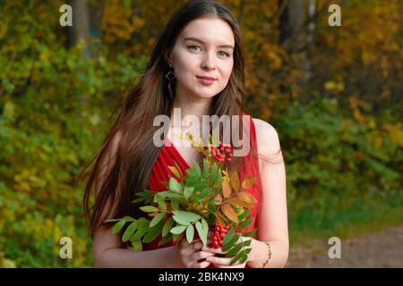 Mädchen in rotem Kleid mit einem Strauß von Eschen in den Wäldern Stockfoto