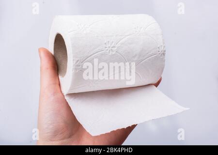 Eine weibliche Hand nimmt eine Rolle weißes Toilettenpapier in die Hand. Stockfoto