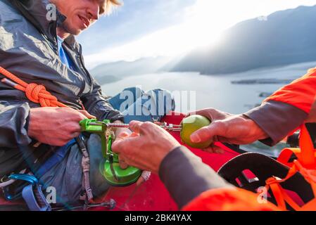 Zwei Männer mit einem Apfelschäler sitzen auf portaledge an Sonnenuntergang Stockfoto