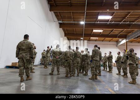 Zugführer und Leutnant John Lambert spricht am 1. Mai 2020 bei einem kurzen Brief an die Food Lifeline Covid-19 Response Food Bank in Seattle mit Soldaten. Food Lifeline hat zusammen mit SSA Marine, Columbia Hospitality und Prologis mit Unterstützung der Washington Army und der Air Force National Guard eine zusätzliche 160,000 Quadratmeter große Lebensmittelbank geschaffen, um auf die steigende Nachfrage nach Nahrungsmitteln in der Region inmitten der COVID-19-Pandemie zu reagieren. Stockfoto