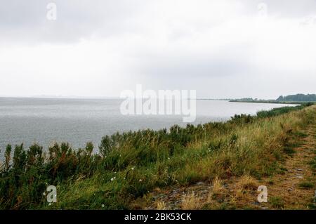 Regnerisches Wetter auf dem Meer, wo die Küste mit grünem Gras sichtbar ist Stockfoto