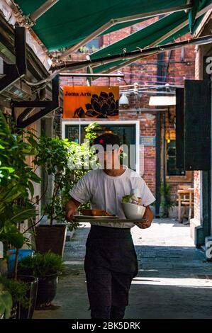 Ein Kellner mit einem Tablett mit Essen im Bereich der Tianzifang Shanghai, China. Stockfoto