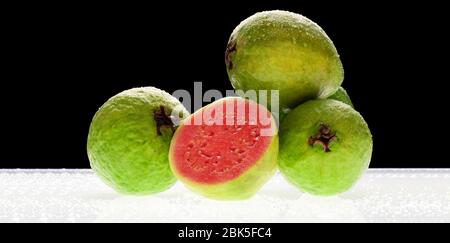 Guava in Scheiben geschnitten mit Hintergrundbeleuchtung auf schwarzem Hintergrund. Stockfoto