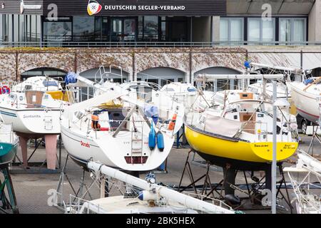 Kiel, Deutschland. Mai 2020. Segelboote werden vor dem Büro des Deutschen Segelverbandes im Olympiahafen in Kiel-Schilksee abgestellt. Ab dem 4. Mai sind die Yachthäfen in Schleswig-Holstein wieder geöffnet. Ausgestattet mit einer Gesichtsmaske, können private Bootsbesitzer dann ihre Boote Kran. Auch nicht-Schleswig-Holsteinische Einwohner dürfen wieder kommen. Quelle: Frank Molter/dpa/Alamy Live News Stockfoto