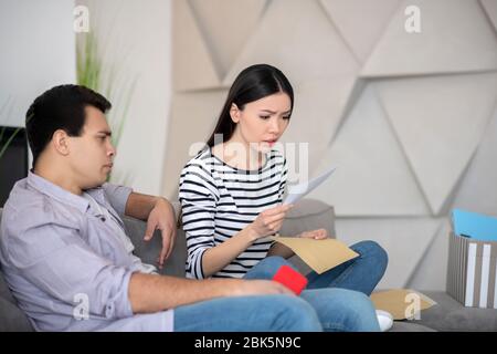 Frau liest Brief in der Nähe Mann mit Smartphone. Stockfoto