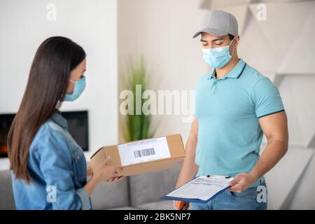 Mann mit Dokument, Frau mit Paket, in Schutzmasken. Stockfoto