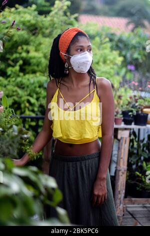 Junge Frau kümmert sich um den Garten während der Sperrung des Coronavirus in Kolumbien Stockfoto
