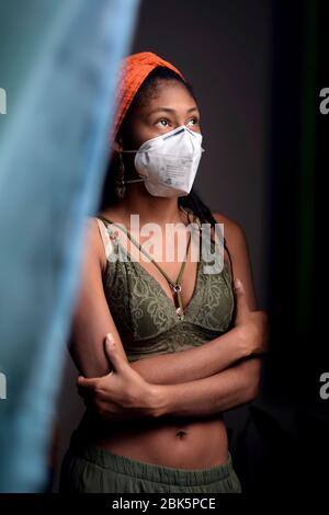 Porträt einer jungen Frau, die während der Sperrung des Coronavirus in Kolumbien Gesichtsmaske trägt und nach draußen schaut Stockfoto