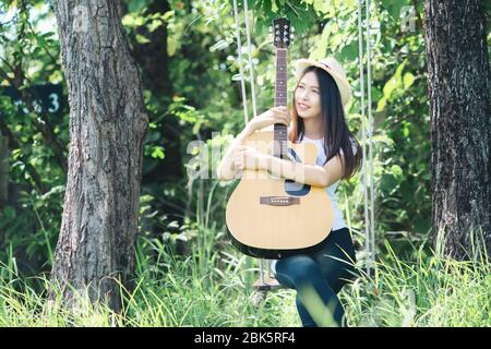 Schöne junge Frau mit Akustikgitarre im Naturhintergrund Stockfoto