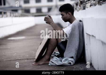 Der arme Mann bittet Almosen, obdachloser Asiat bettelt um Geld Stockfoto
